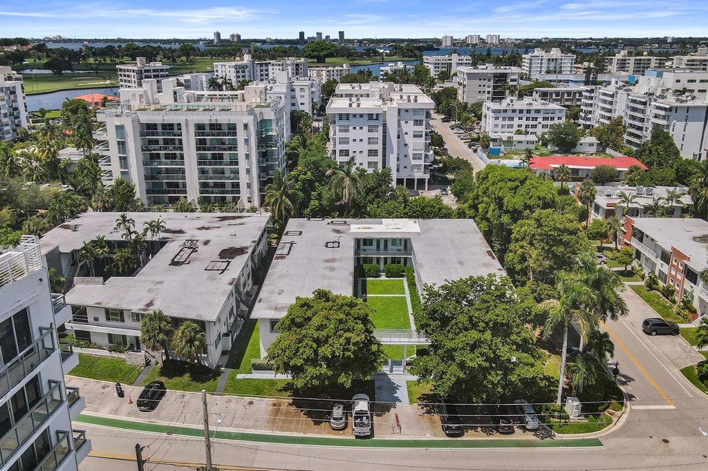 A view of a cityscape with buildings, trees, and a parking lot.