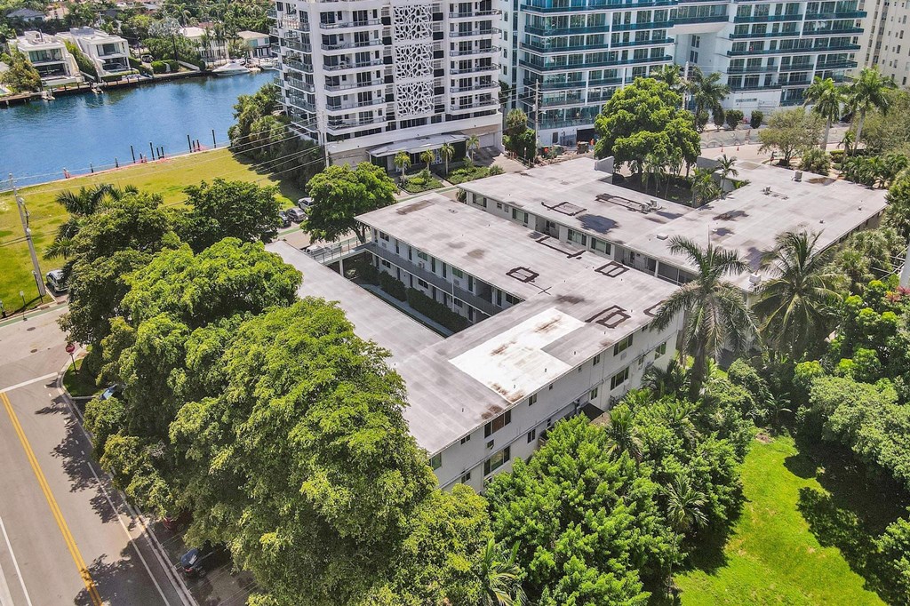 A large white building surrounded by trees and a body of water.