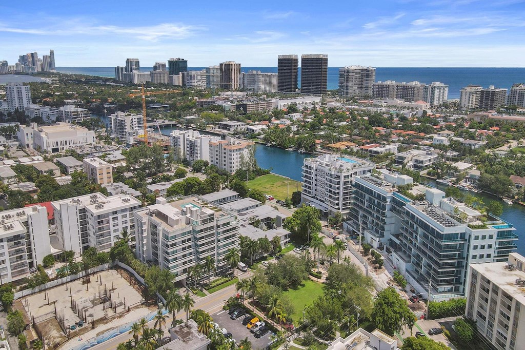 A cityscape with a mix of residential and commercial buildings, a body of water, and a clear sky.