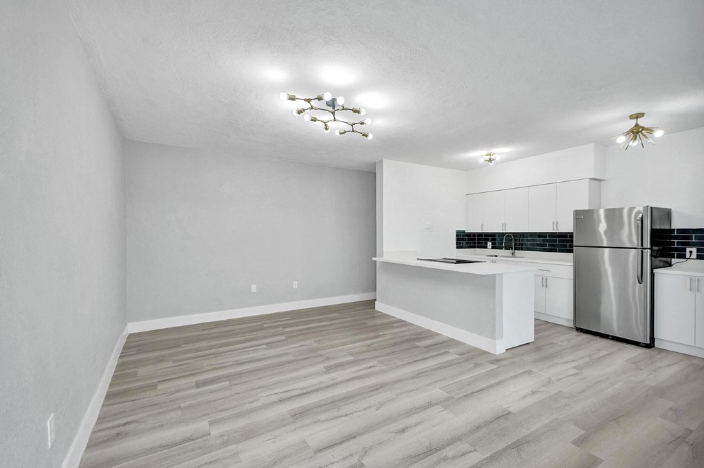 A kitchen with a refrigerator, sink, and cabinets.