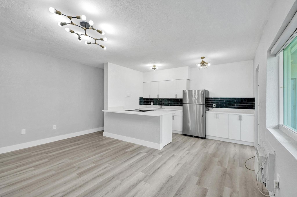 A kitchen with white cabinets and a wooden floor.