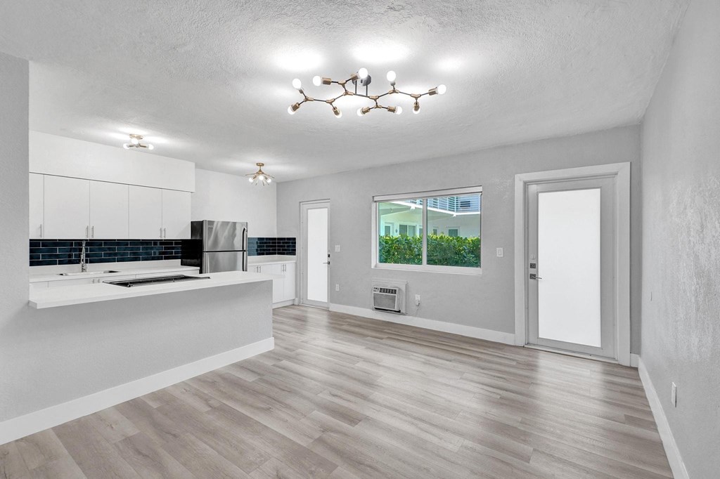 A spacious kitchen with wooden floors and white walls.