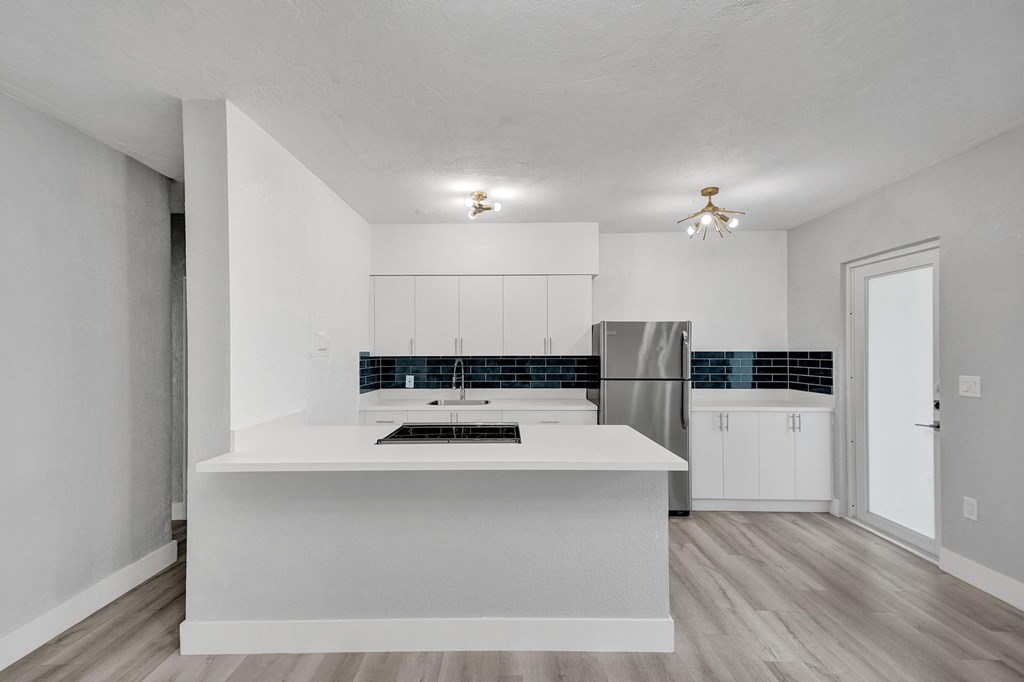 A modern kitchen with a white island and wooden floors.