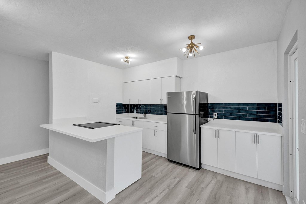 A modern kitchen with a stainless steel refrigerator and white cabinets.
