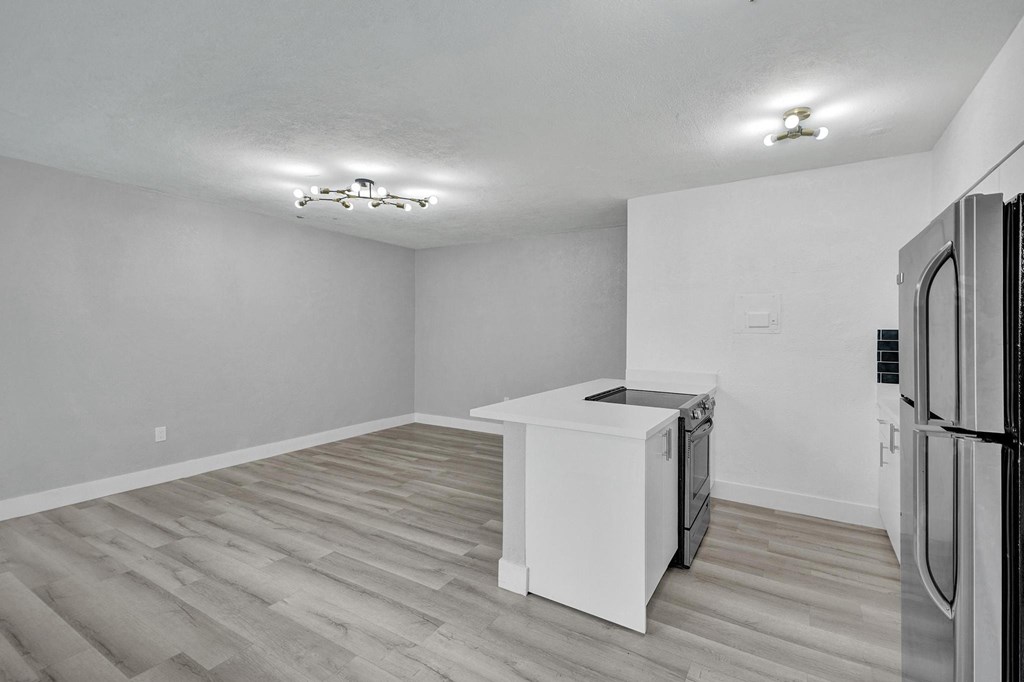 A kitchen with a white fridge and wooden flooring.