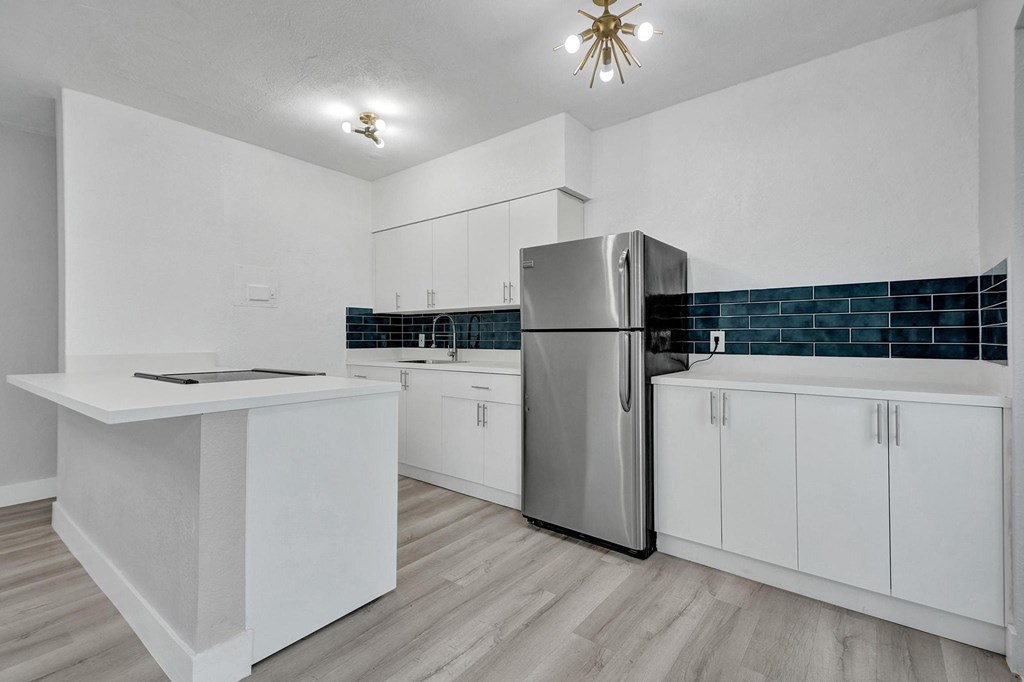 A kitchen with white cabinets and a stainless steel refrigerator.