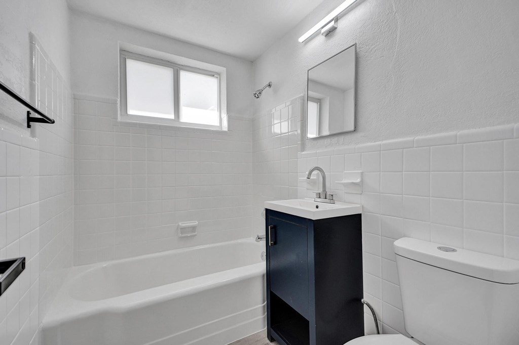 A white bathroom with a tub, sink, and toilet.