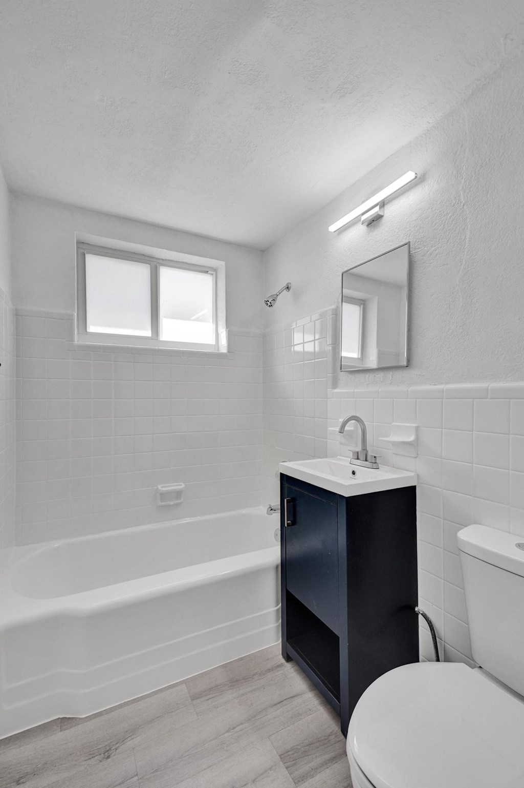 A white bathroom with a black cabinet and a white toilet.