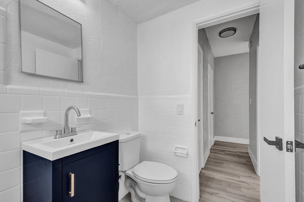 A bathroom with a white toilet and a sink with a cabinet underneath it.