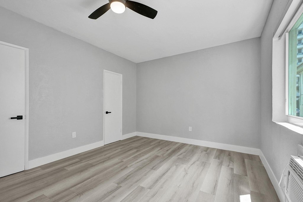 A room with a ceiling fan and wooden flooring.