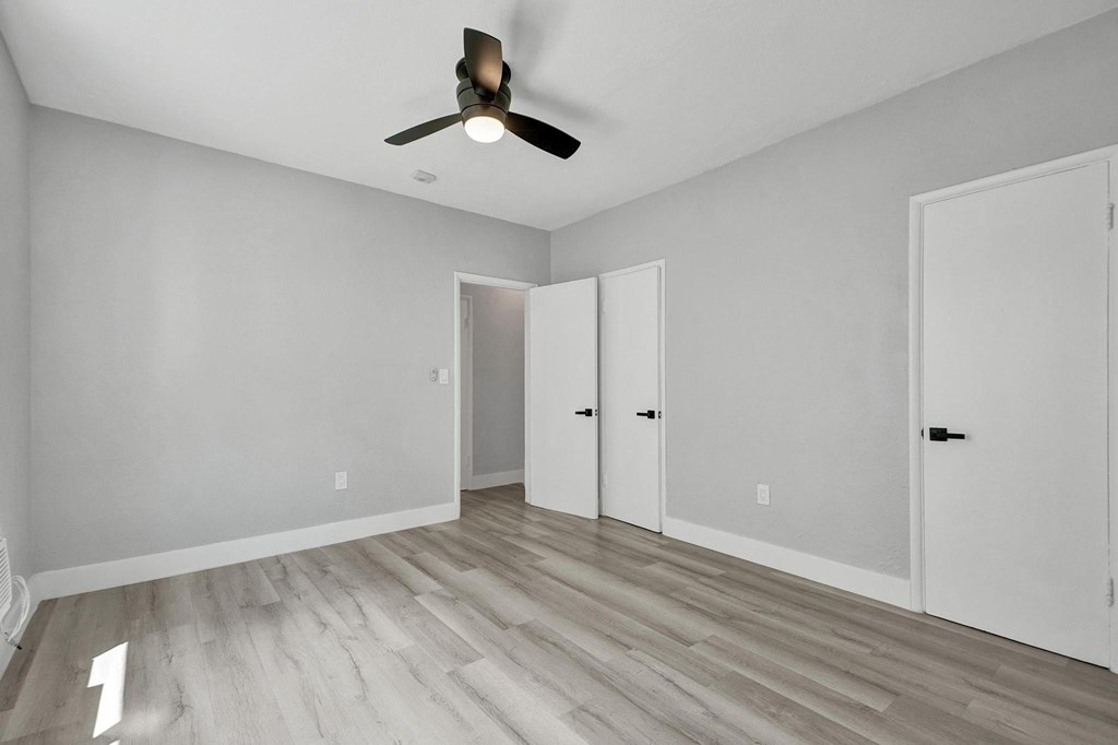 A room with a ceiling fan and three doors.