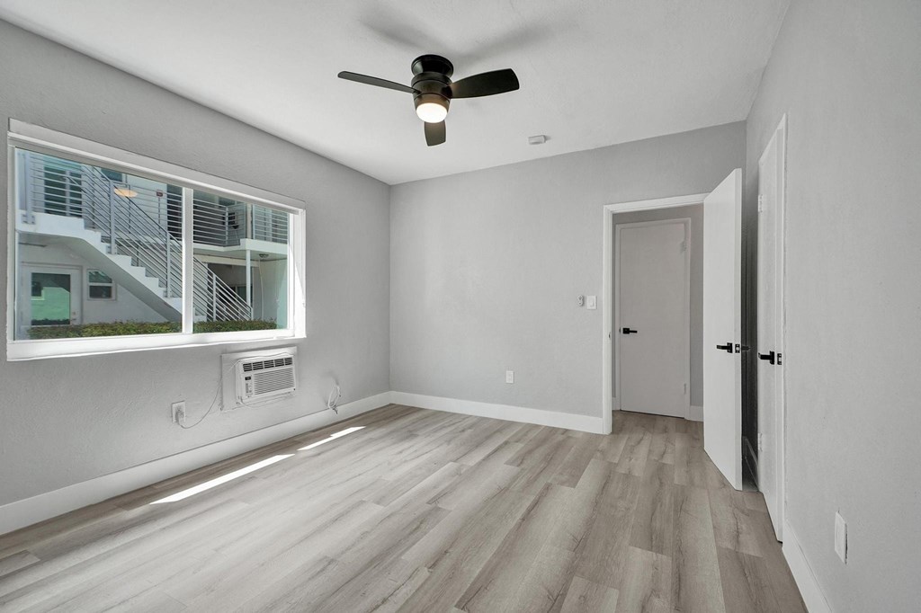A room with a ceiling fan and a window with a view of a staircase.
