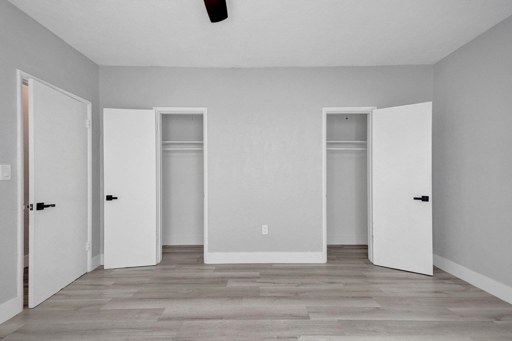 Three white doors in a room with wood flooring and white walls.