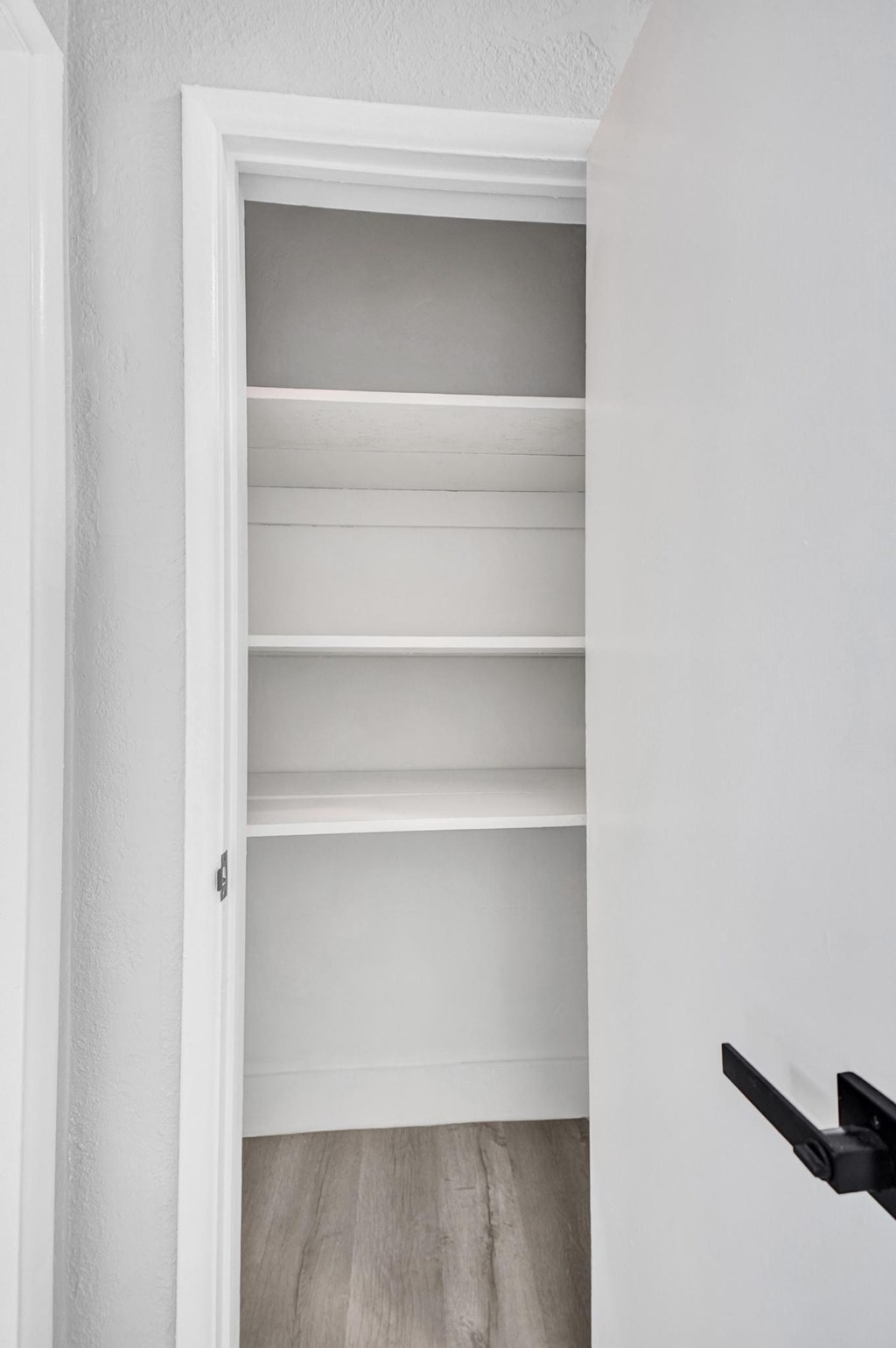 A white door with a black handle and a white shelf.