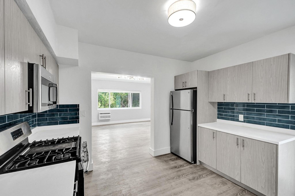 A kitchen with a stove, refrigerator, and cabinets.