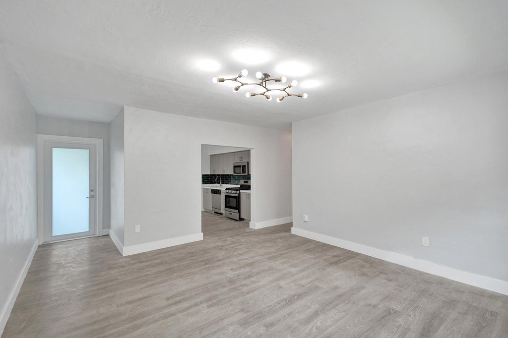 A large empty room with a kitchen in the background.