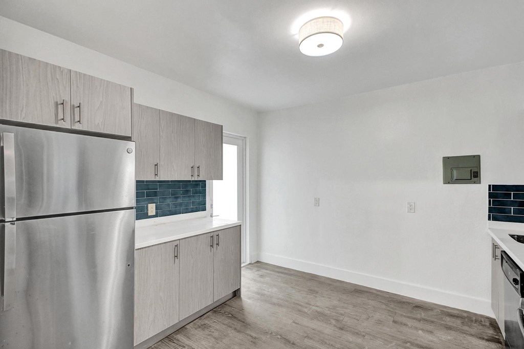 A kitchen with a stainless steel refrigerator and wooden cabinets.