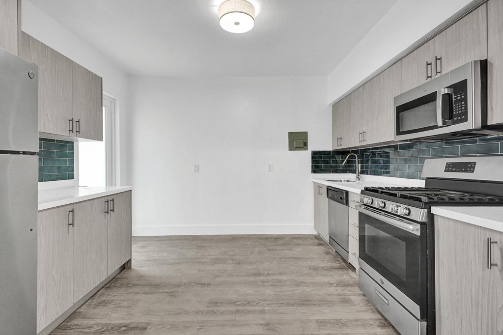 A kitchen with a black stove top oven and a microwave above it.