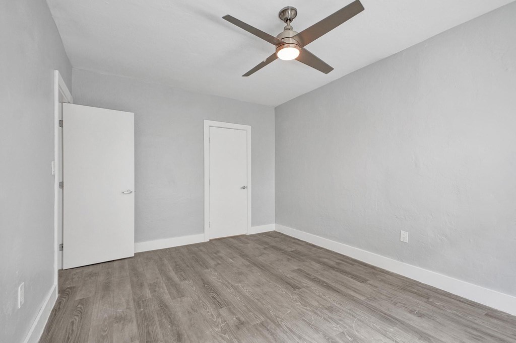 A room with a ceiling fan and wood flooring.