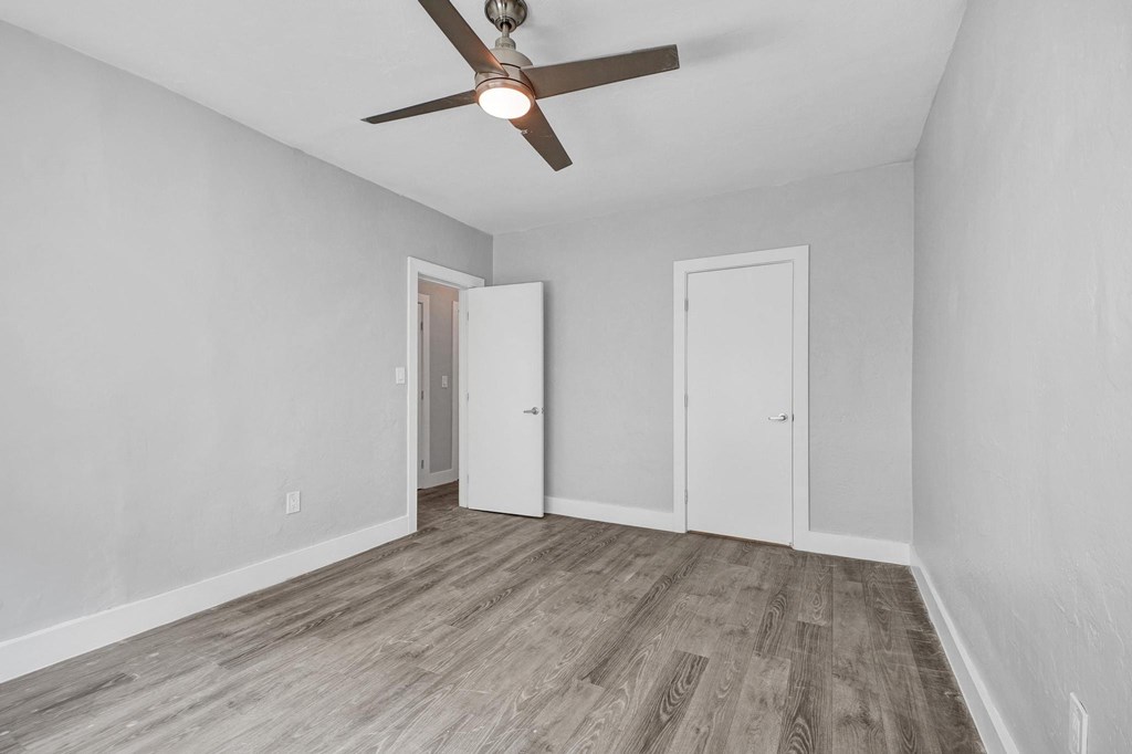 A room with a ceiling fan and wood flooring.