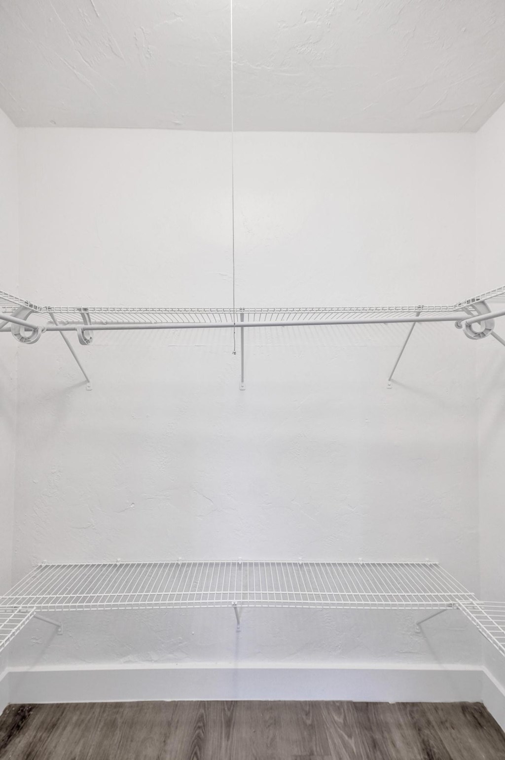 A white wall with a metal rack and a white bench.
