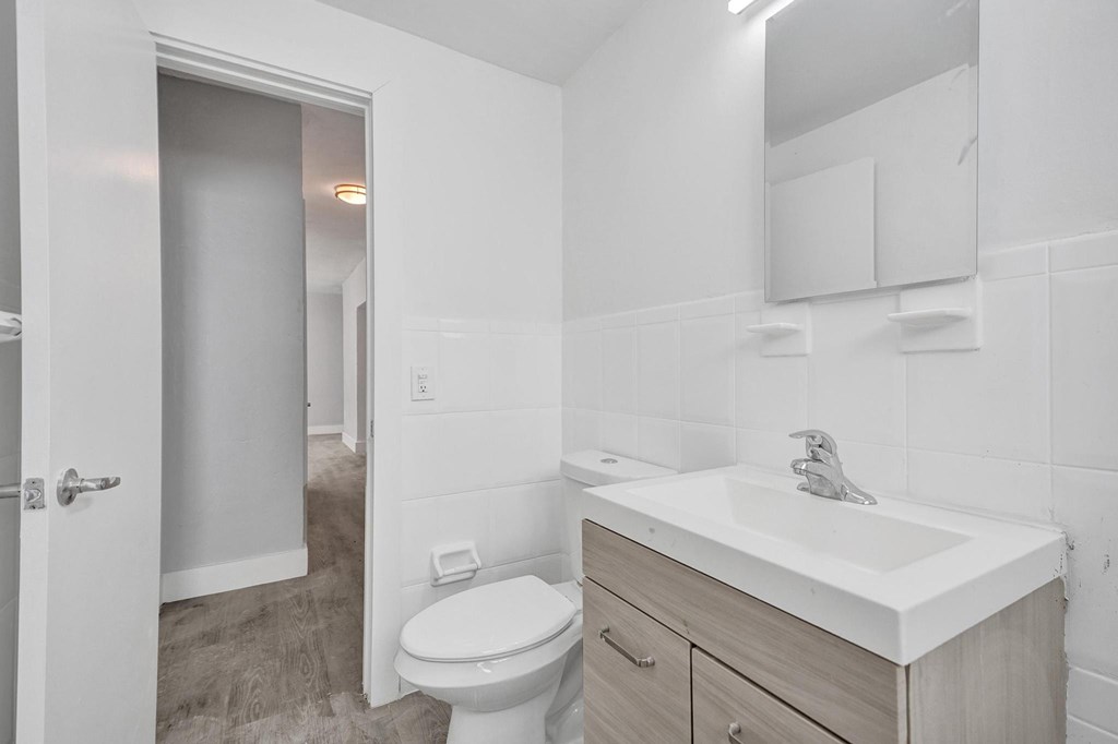 A white bathroom with a toilet, sink, and mirror.