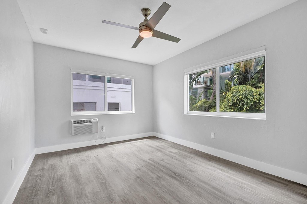 A room with a ceiling fan and a window showing a view of trees.