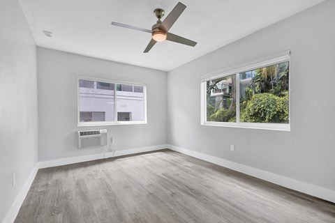 A room with a ceiling fan and a window showing a view of trees.