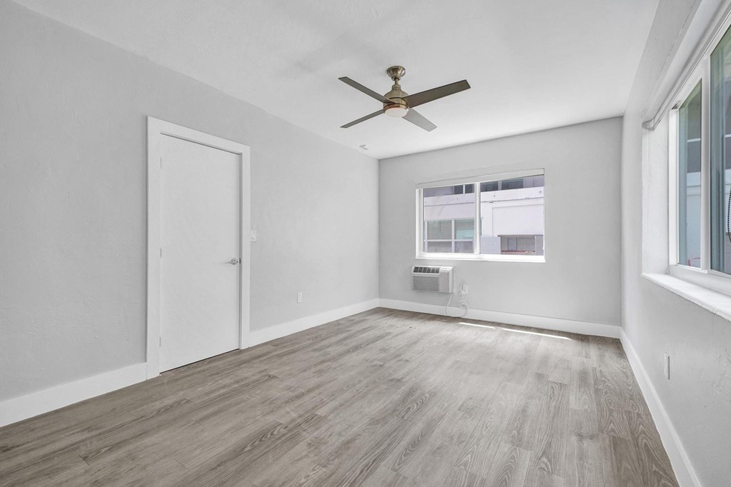 A room with a ceiling fan and a window with blinds.