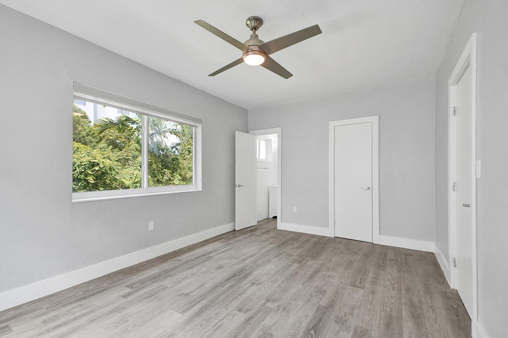 A room with a ceiling fan and a large window.