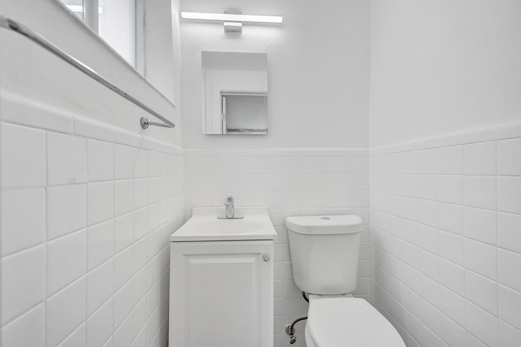 A white bathroom with a toilet, sink, and mirror.
