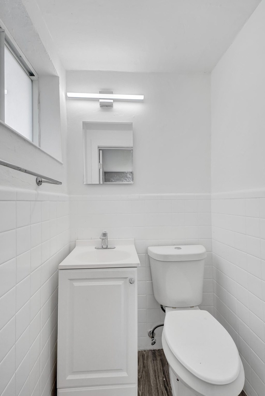 A white bathroom with a toilet, sink, and mirror.