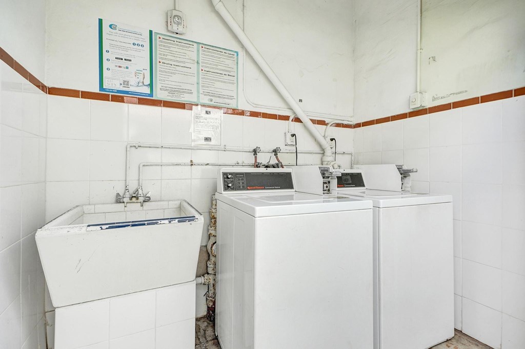 A bathroom with a white sink and a white washing machine.