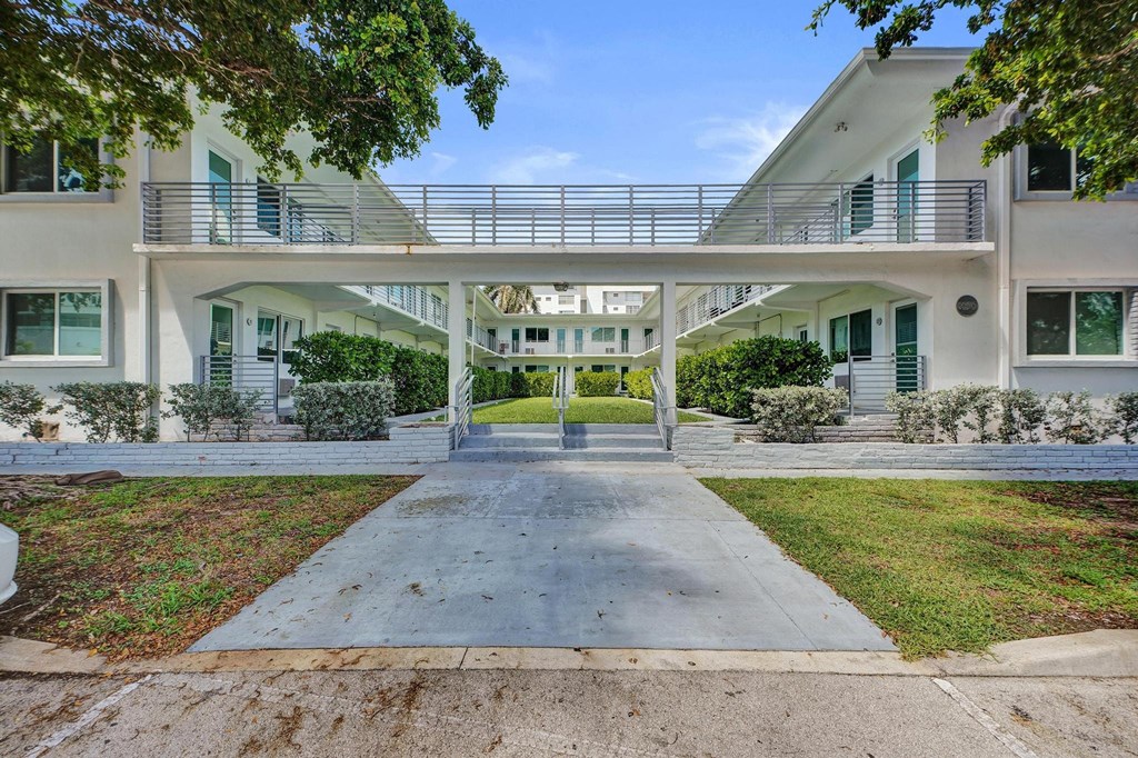 A white building with a balcony and a walkway in front.