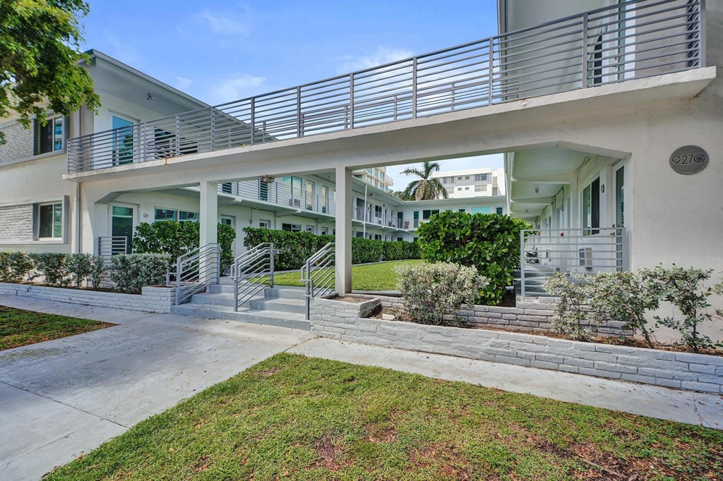 A white building with a balcony and stairs leading to the entrance.