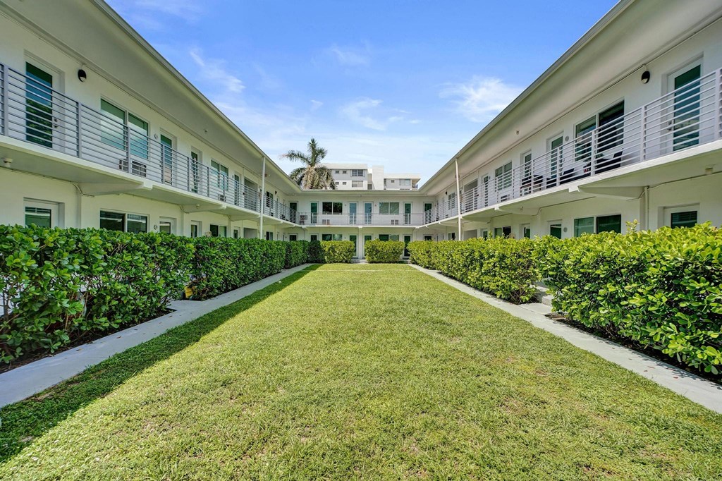 A long white building with green bushes on the sides.