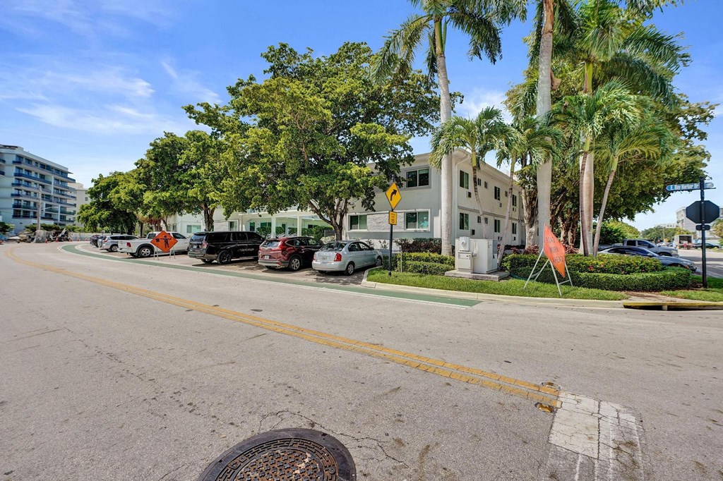 A street view with cars parked on the side and a building in the background.
