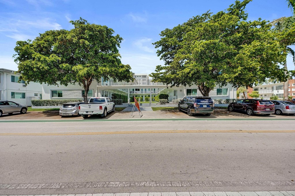 A street view with cars parked on the side and trees in the background.