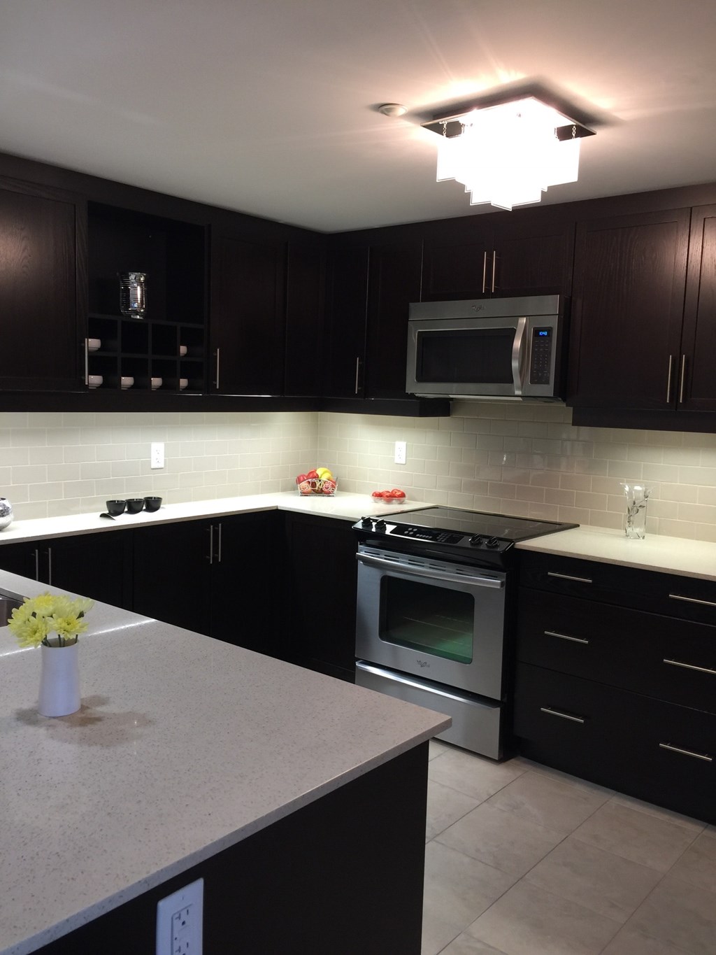 A kitchen with black cabinets and a stainless steel oven.