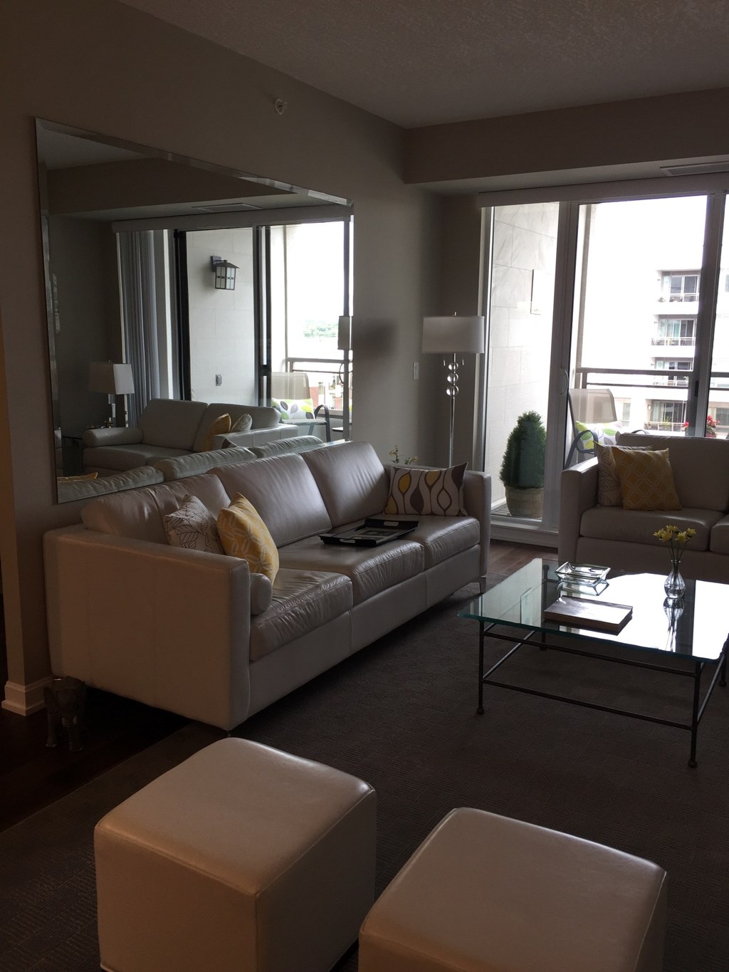 A living room with a grey couch and a glass coffee table.
