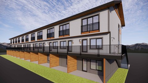 A modern two-story building with balconies and a mountainous backdrop.