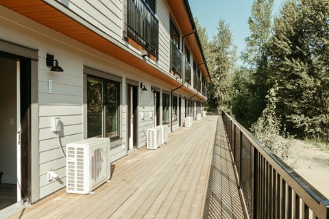 A long wooden deck with air conditioning units on it.