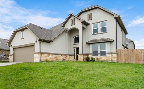 A large, two-story house with a garage and a fence in front.