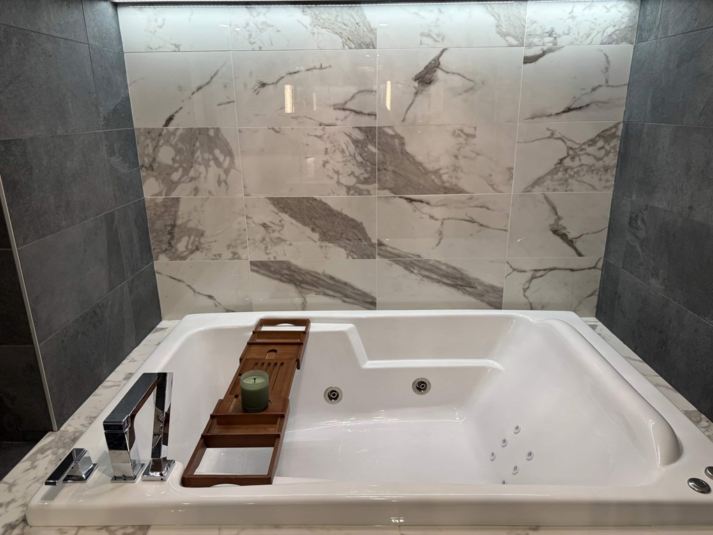 A white bathtub with a wooden tray on it.