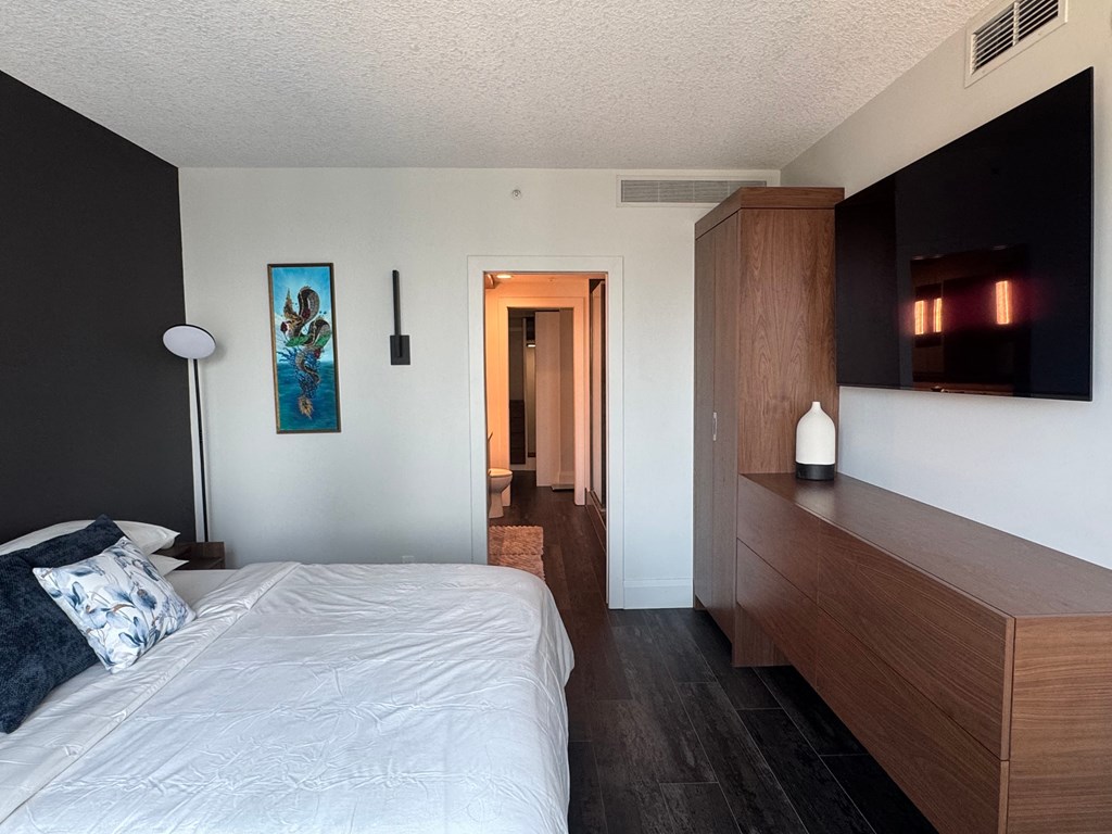 A bedroom with a bed, nightstand, and a painting on the wall.