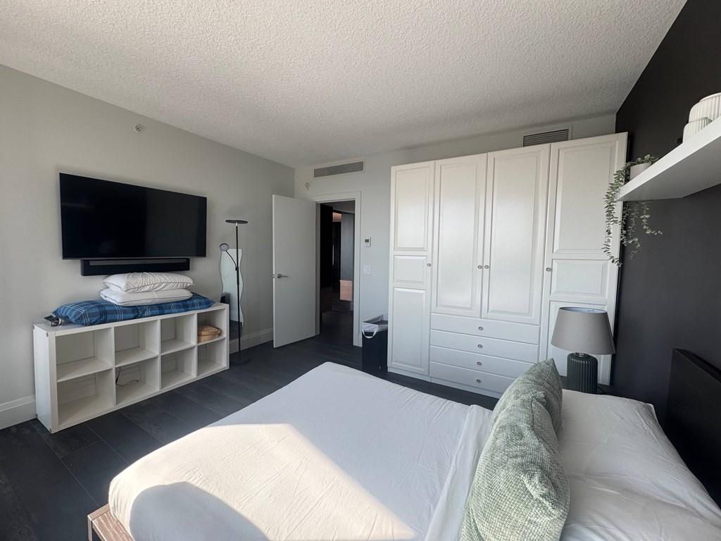 A bedroom with a bed, a TV, and a cabinet.