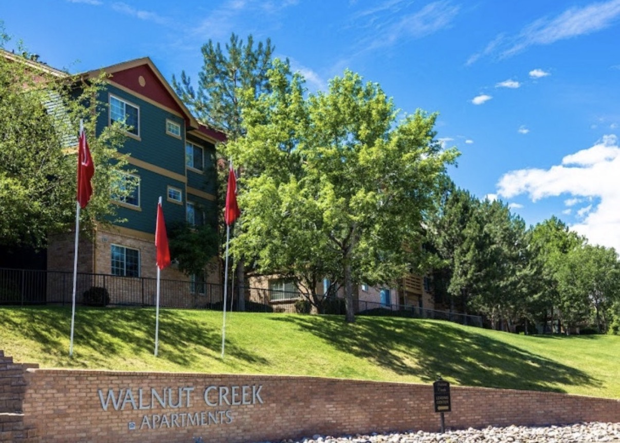 A sign that says Walnut Creek Apartments in front of a building.