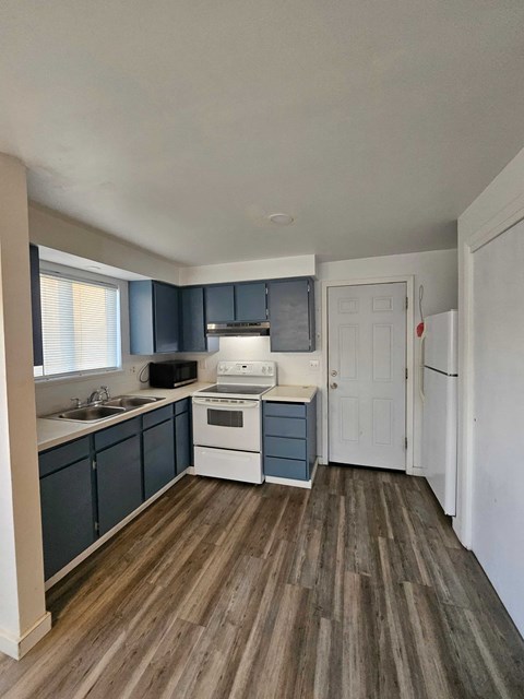 A kitchen with a white stove top oven and white cabinets.