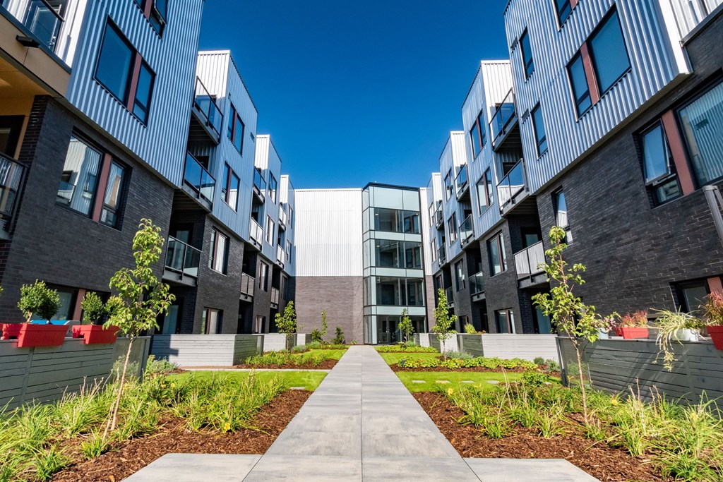 A modern apartment complex with a walkway in the middle of the courtyard.