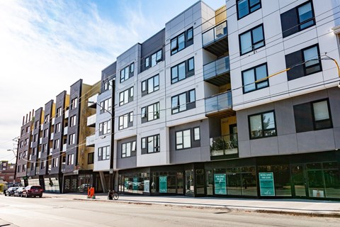 A modern multi-story building with balconies and glass doors.